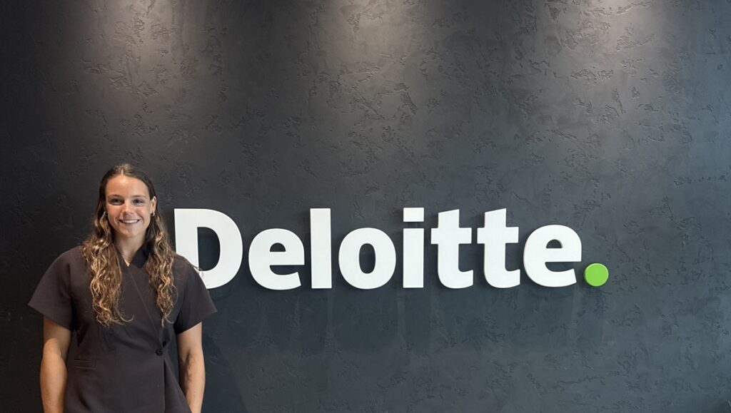 Kate Haines in front of a Deloitte sign